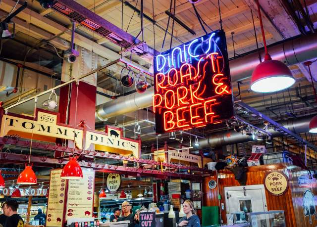A neon sign in a market that reads DiNics Roast Pork and Beef