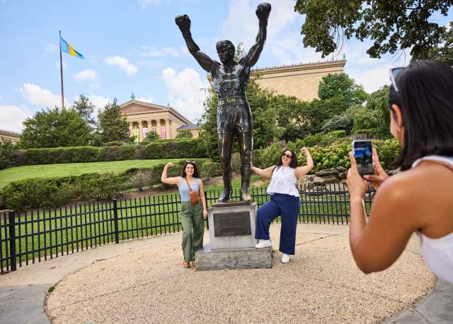 Two Hispanic women pose for a photo in Philadelphia by the Rocky Statue