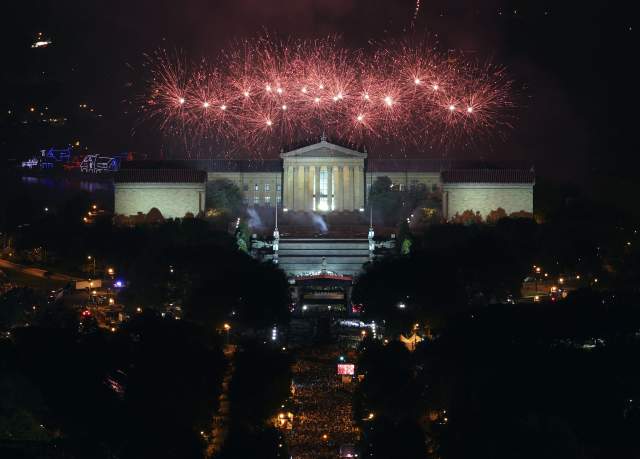 Fireworks going off above the Philadelphia Art Museum at night with a large crowd watching