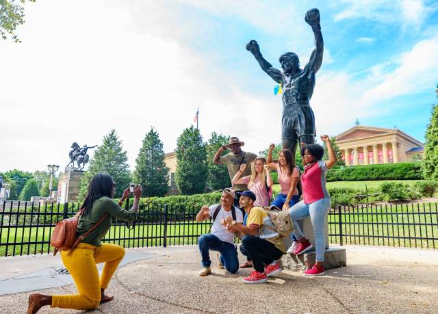 Group of people posing for photo a Rocky Statue at the Philadelphia Museum of Art