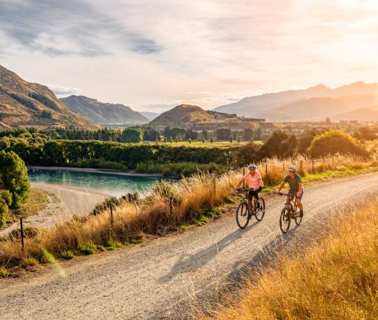 A couple cycle the Twin Rivers Trail in the evening summer light