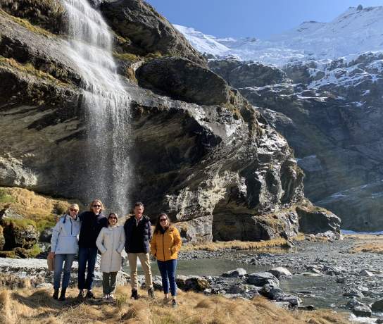 A group of people posing in front of a glacial waterfall