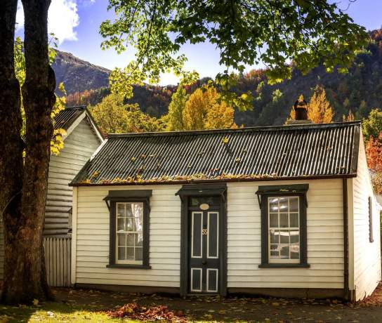 External view of old cottage surrounded by autumn trees