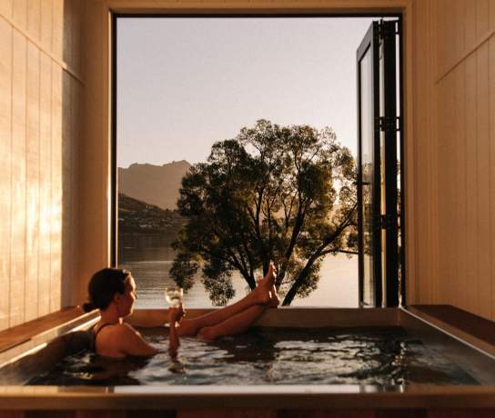 Woman relaxing with a glass of win in a hot tub at Driftaway, Queenstown