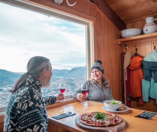 Couple enjoying pizza and wine at Heidi's Hut on Coronet Peak