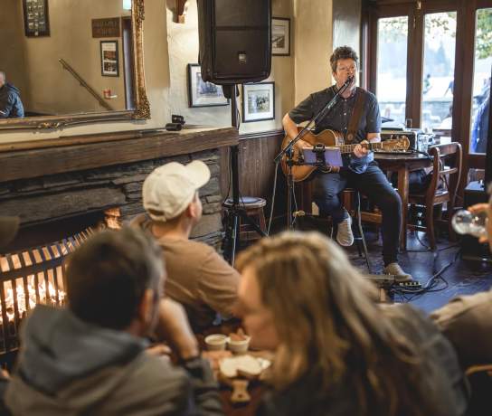 Musician playing guitar to people at Pog Mahones Irish Pub
