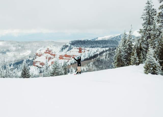 Snowboarding at Brian Head Resort with beautiful red rock in the background.