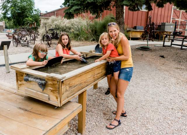 A mom and three kids pan for gold outside at the Frontier Homestead State Park Museum in Cedar City, Utah.