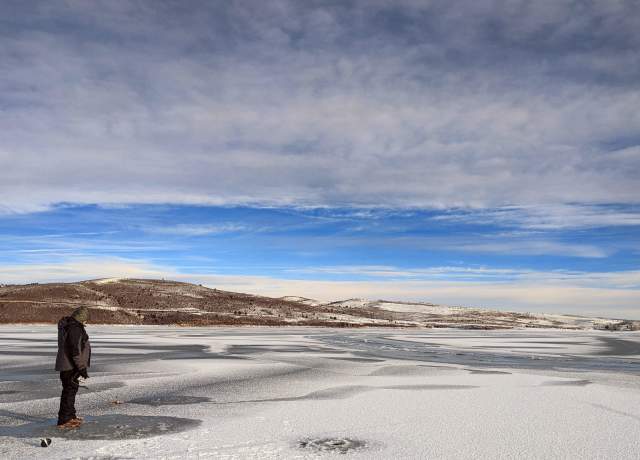 A fisherman stands on ice at Panguitch Lake in Utah.