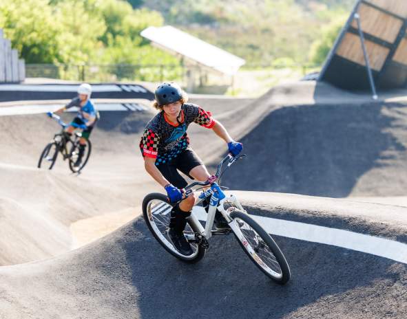 2 kids riding in a pump track
