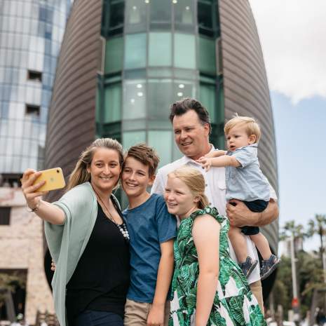 A family pose for a photo in front of The Bell Tower in Perth City