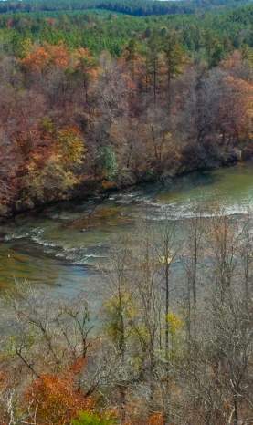 An aerial shot of Cahaba River Park shows fall foliage over the free flowing Cahaba River.