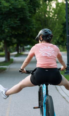 Person biking wearing Peach Kelowna Mountain Wave T shirt 2