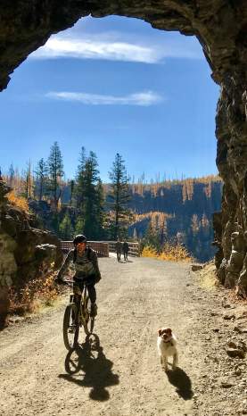 Biking through tunnel at Myra Canyon Trestles During Larch Season