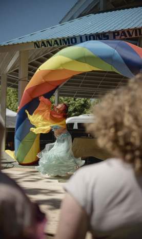 In a flowy dress, a women dances under a rainbow.
