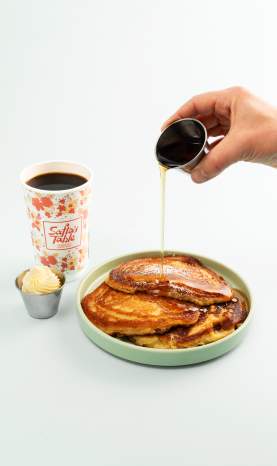 Pouring syrup over buttermilk pancakes at Safta's Table