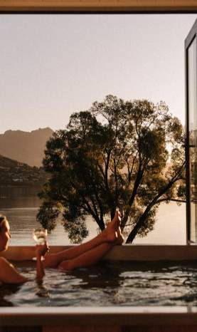 Woman relaxing with a glass of win in a hot tub at Driftaway, Queenstown
