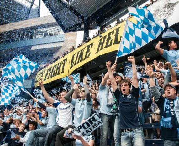 Image shows Sporting KC fans cheering with a sign that reads, "Fight like Hell."