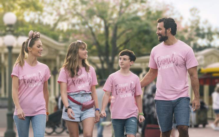 A family of four, in matching pink shirts, walking on Main Street at the Magic Kingdom in the Walt Disney World Resort.