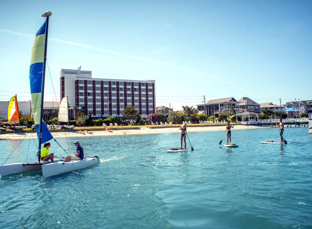 People paddleboarding and sailing at Blockade Runner Resort in Wrightsville Beach.