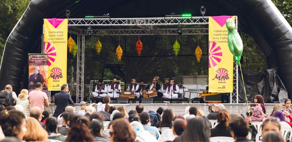 Back of crowd watching Khan Brothers on a stage at Southampton Mela Festival outside in Hoglands Park on a sunny day