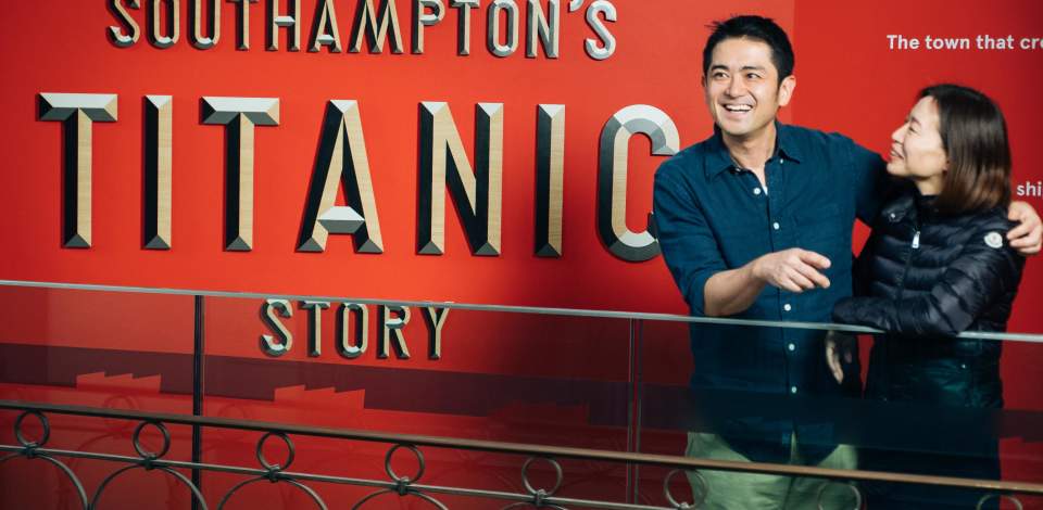Two people stood in front of the Titanic Exhibition sign which reads Southampton's Titanic Story at Seacity Museum