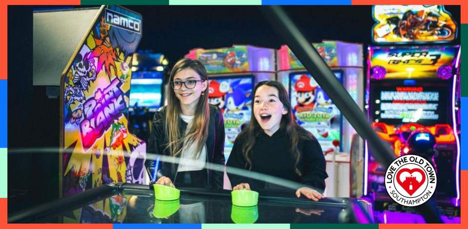 Two girls playing air hockey at High Score Arcades
