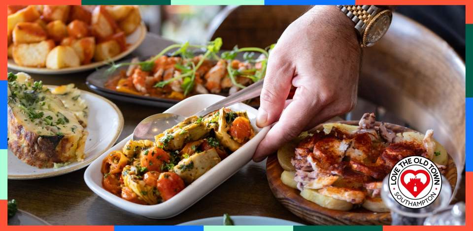 Man placing down dish of roasted vegetables among other Spanish, Mediterranean dishes at La Regata