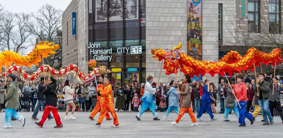 Crowd of people watching Chinese dragon dance in Guildhall Square