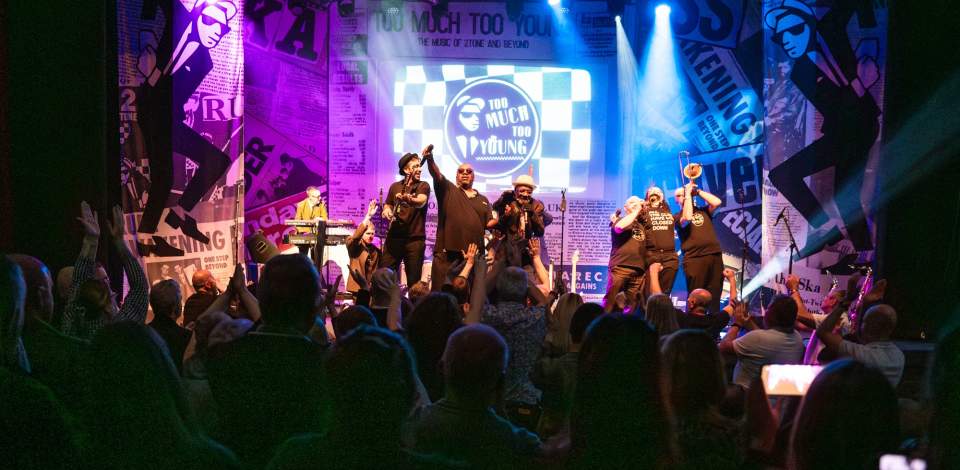 Too Much Too Young performing on stage in front of a crowed