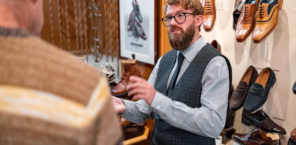 A person holding a shoe in W J French & Sons shoe shop showing a customer