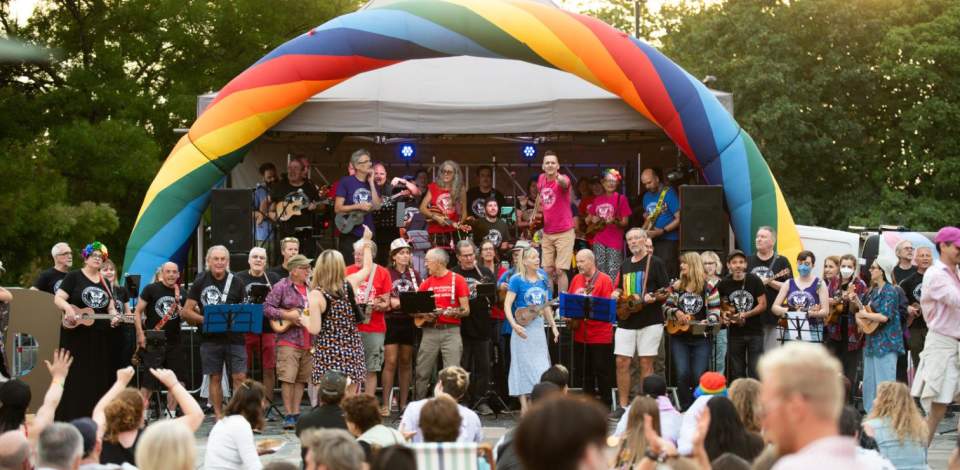 Large group of Ukulele players, from Southampton Ukulele Jam, playing in front of a crowd at Southampton Pride
