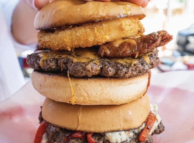 Two Signature Burgers being held on top of one another.