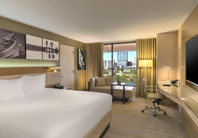 Image of the inside of a hotel hotel room with a bed, lounge chaise and desk at the Hyatt Regency Austin.