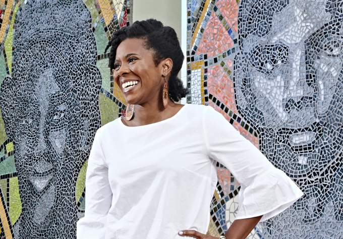 Nefertitti Jackmon stands in front of the mosaic of iconic Black baseball players at Downs Mabson Field in East Austin Texas