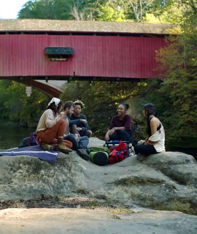 Group of Hikers resting on a rock under a Covered Bridge in Turkey Run State Park