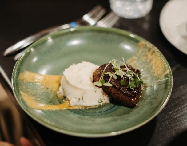 Green plate with filet steak and mashed potatoes.