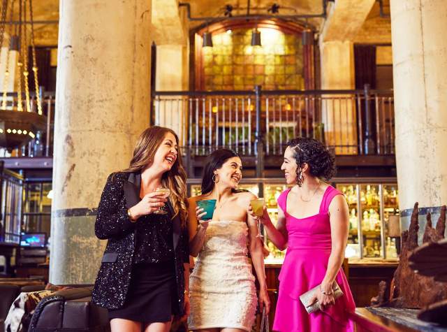 Three girls enjoying drinks in beautiful room with two large pillars