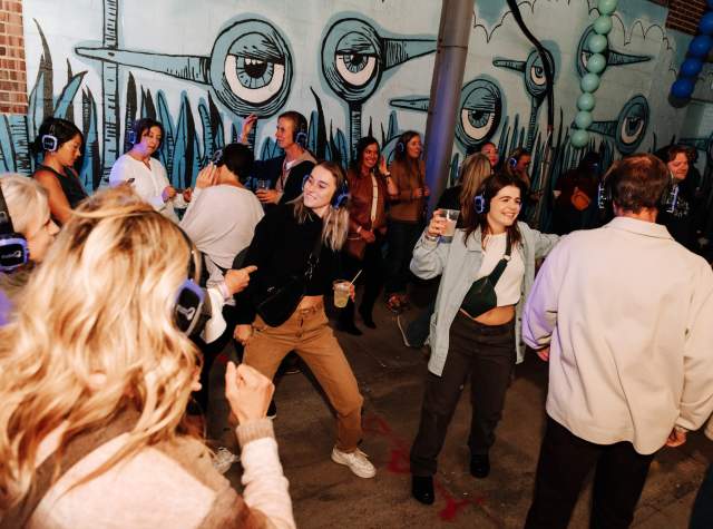 People partying in an alleyway in front of public art in Fort Wayne.