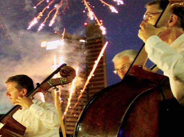 Picture of two musicians playing with fireworks in the background.