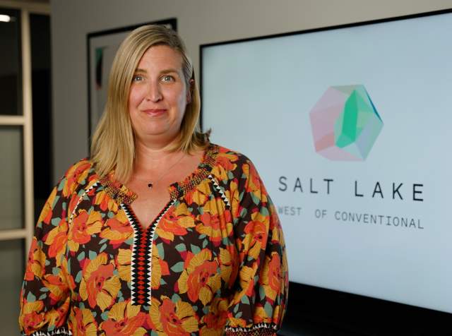 Kaitlin Eskelson standing in front of a white board with the Visit Salt Lake logo