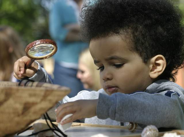 Child with a magnifying glass at the Roger Williams Park Zoo