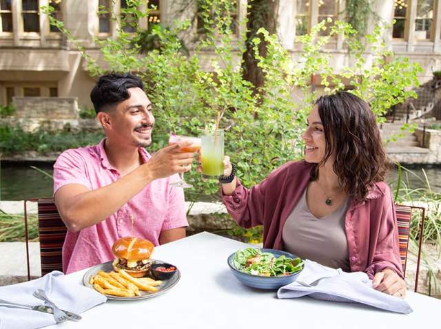 Man and woman toasting on the San Antonio River Walk.