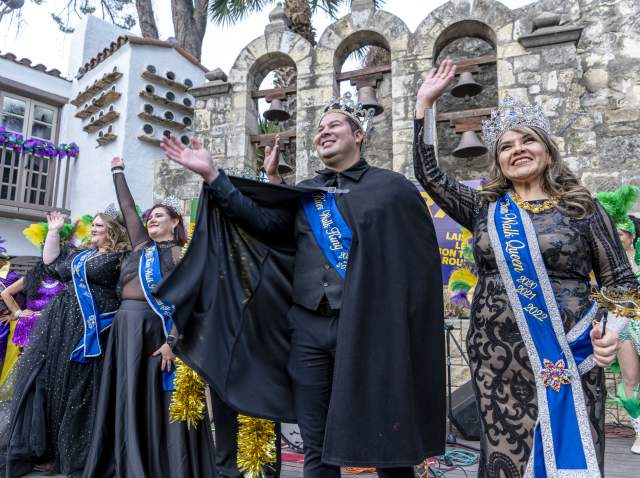 People dressed in costumed royalty waving to crowd at Arneson River Theatre.