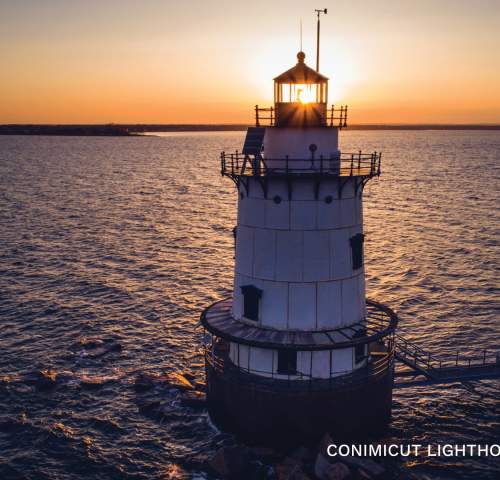 The Conimicut Lighthouse, surrounded by water, at sunset.