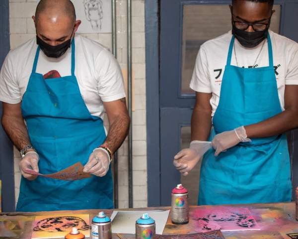 Two people spray painting a canvas Graft Bristol - credit Yuup