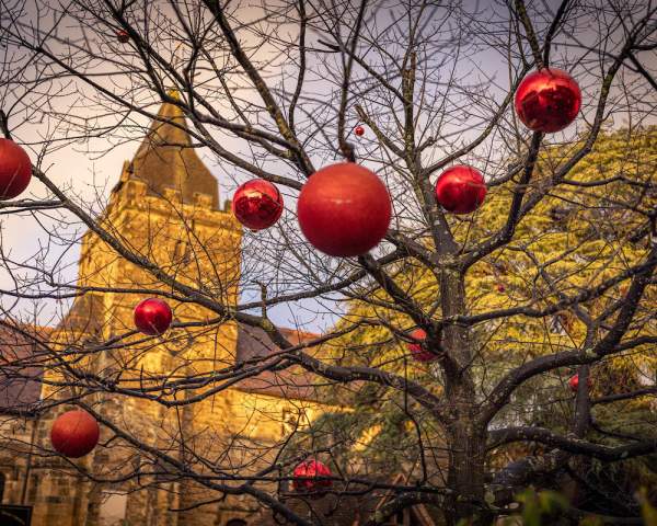 Baubles hang from a tree with a Church in the background