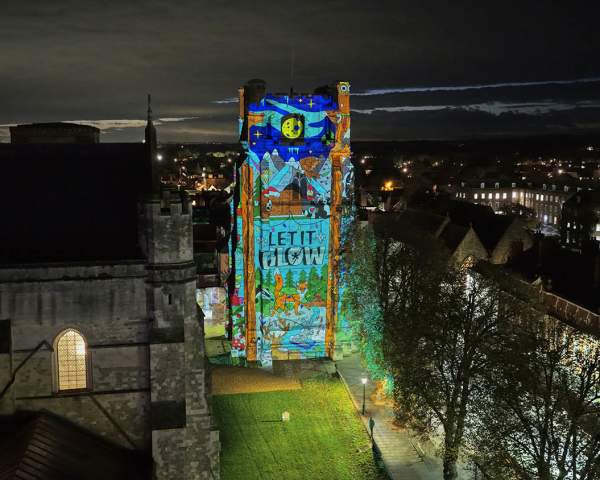 An image showing the bell tower of Chichester Cathedral lit with Christmas images for let it glow