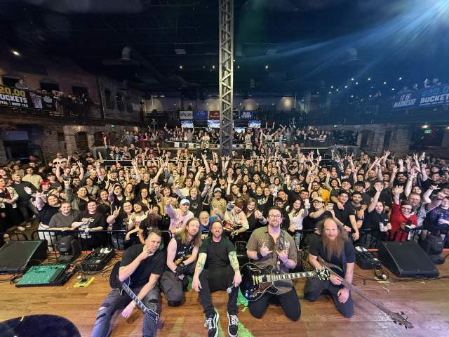 A huge crowd attending a concert posed with the band.