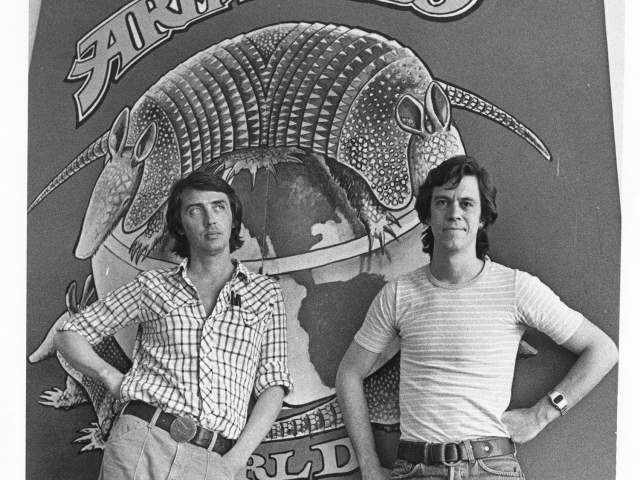 Black and white photo of two men in front of Armadillo World Headquarters sign